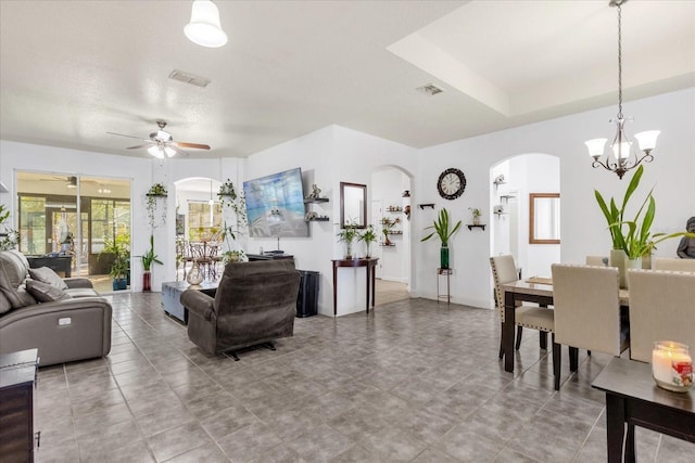 living room featuring ceiling fan with notable chandelier and a tray ceiling