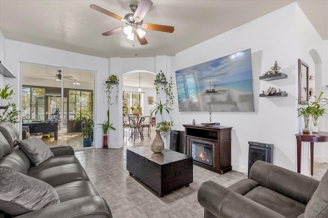 tiled living room with ceiling fan and a textured ceiling