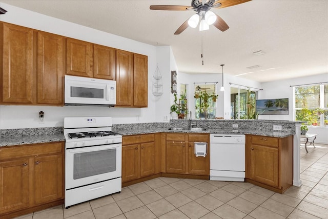 kitchen with kitchen peninsula, ceiling fan, white appliances, light stone counters, and sink