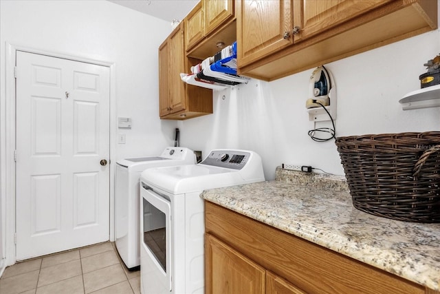 laundry room with cabinets, light tile patterned floors, and washing machine and clothes dryer