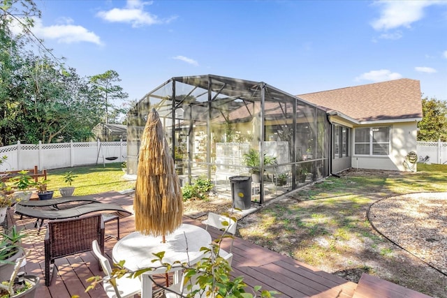 exterior space with glass enclosure, a wooden deck, and a lawn