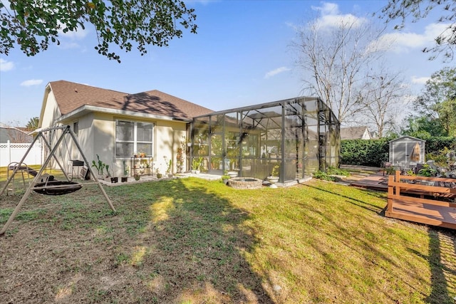 view of yard featuring glass enclosure, a wooden deck, and a fire pit