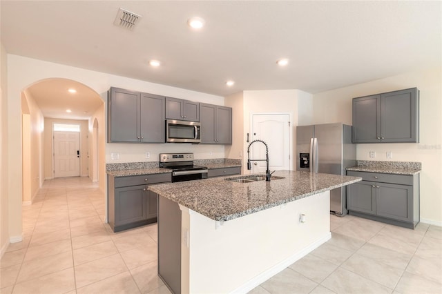 kitchen featuring gray cabinets, sink, a center island with sink, and stainless steel appliances