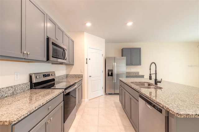 kitchen featuring a center island with sink, gray cabinets, appliances with stainless steel finishes, light tile patterned flooring, and sink