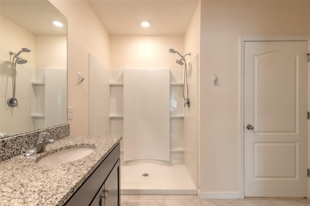 bathroom with walk in shower, vanity, and tile patterned flooring