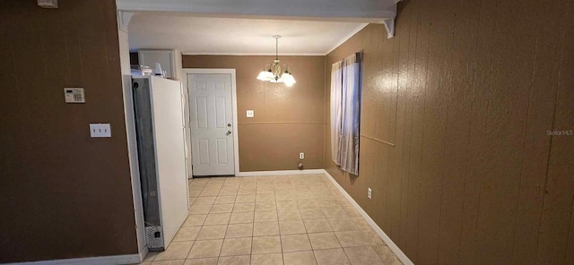 interior space featuring light tile patterned floors, a notable chandelier, wood walls, and ornamental molding