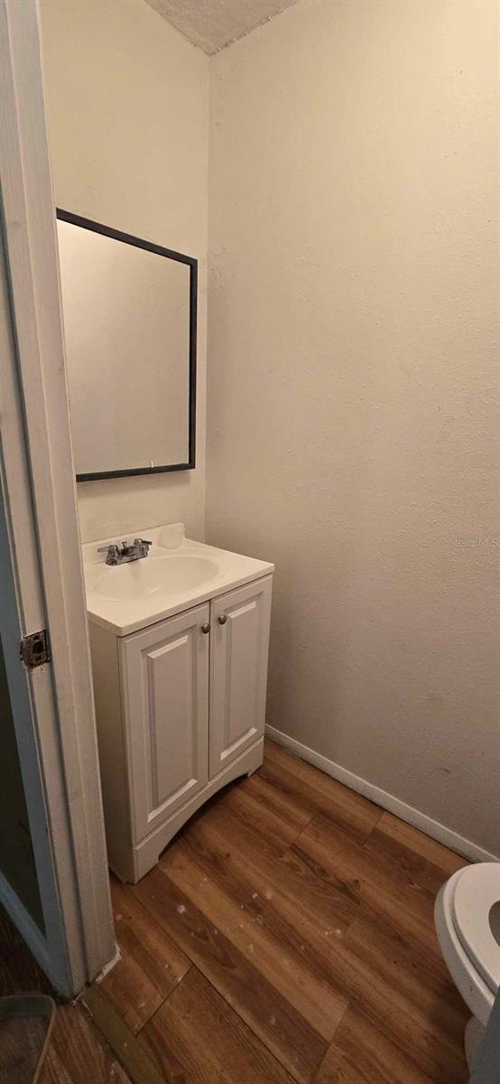 bathroom with toilet, vanity, wood-type flooring, and a textured ceiling