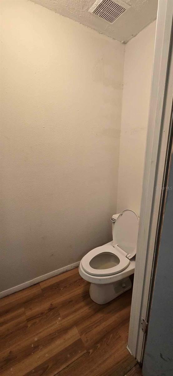 bathroom with hardwood / wood-style floors, toilet, and a textured ceiling