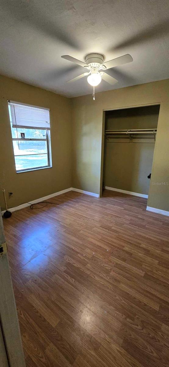 unfurnished bedroom with a textured ceiling, ceiling fan, a closet, and dark hardwood / wood-style floors