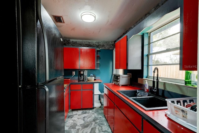 kitchen with black refrigerator, a textured ceiling, and sink