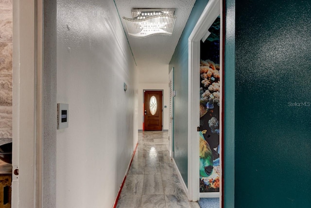 hall featuring a notable chandelier and a textured ceiling