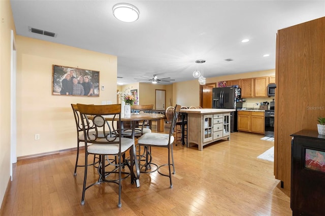 kitchen featuring light hardwood / wood-style floors, ceiling fan, stainless steel appliances, hanging light fixtures, and a center island