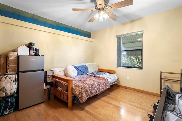 bedroom with ceiling fan, stainless steel fridge, and light hardwood / wood-style flooring