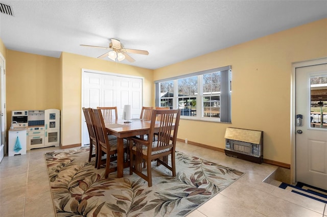 dining area with a textured ceiling, ceiling fan, light tile patterned floors, and heating unit