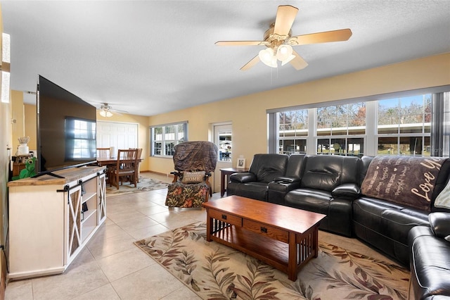 living room featuring ceiling fan, a textured ceiling, a healthy amount of sunlight, and light tile patterned flooring