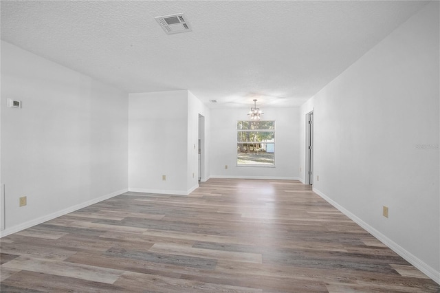 unfurnished room featuring wood-type flooring, a chandelier, and a textured ceiling