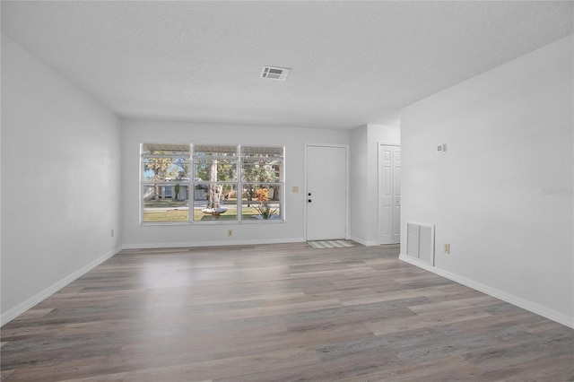 unfurnished room with hardwood / wood-style flooring and a textured ceiling