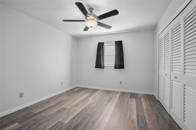 unfurnished bedroom with a textured ceiling, a closet, hardwood / wood-style flooring, and ceiling fan