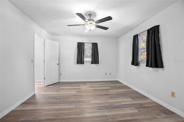 spare room featuring a textured ceiling, a healthy amount of sunlight, and hardwood / wood-style floors