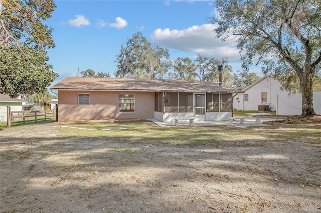 back of property featuring a sunroom, a lawn, and a patio