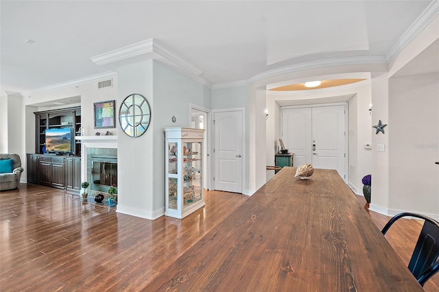 dining room with dark wood-type flooring, ornamental molding, and built in shelves