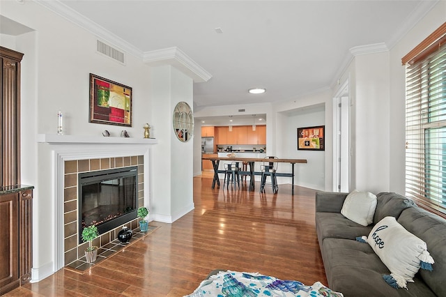 living room featuring wood-type flooring, a fireplace, and ornamental molding