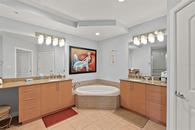 bathroom with tiled tub, vanity, and tile patterned flooring