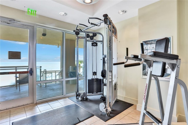 workout area featuring light tile patterned floors and a water view