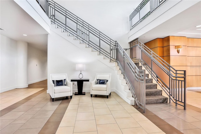 stairway featuring tile patterned flooring and a high ceiling