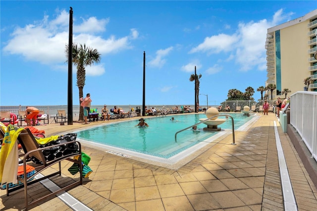 view of swimming pool with a patio area and a water view