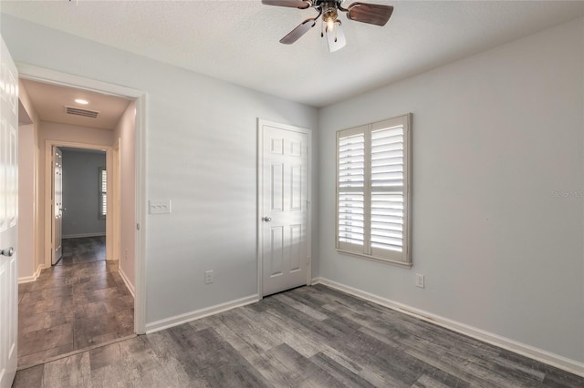 unfurnished bedroom with dark wood-type flooring, ceiling fan, and a closet