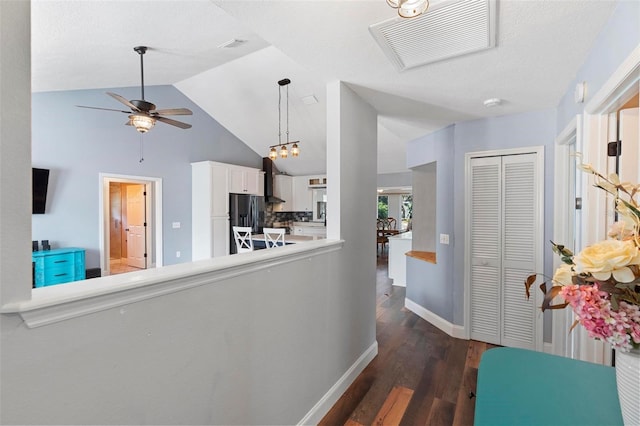 corridor with lofted ceiling, dark hardwood / wood-style floors, and a notable chandelier