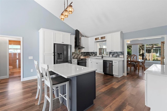 kitchen featuring white cabinetry, appliances with stainless steel finishes, tasteful backsplash, hanging light fixtures, and wall chimney range hood