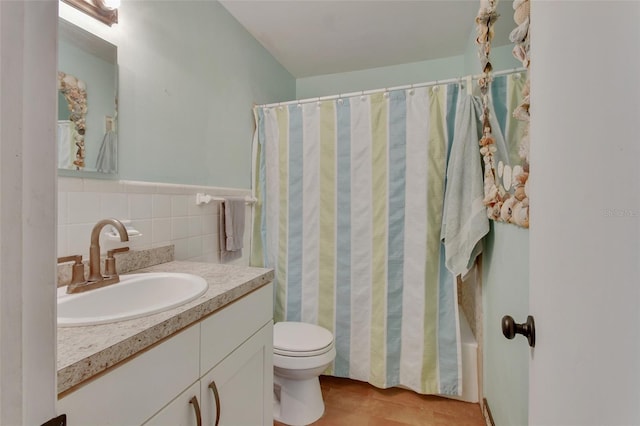 bathroom with toilet, tile walls, and vanity