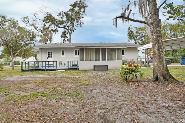 back of house with a deck, a sunroom, and a carport