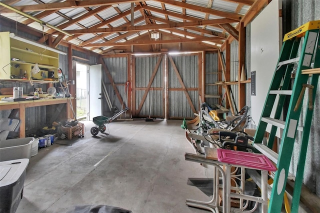 misc room with lofted ceiling, a workshop area, and concrete floors