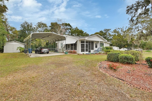 back of house with a shed, a carport, a yard, and a sunroom