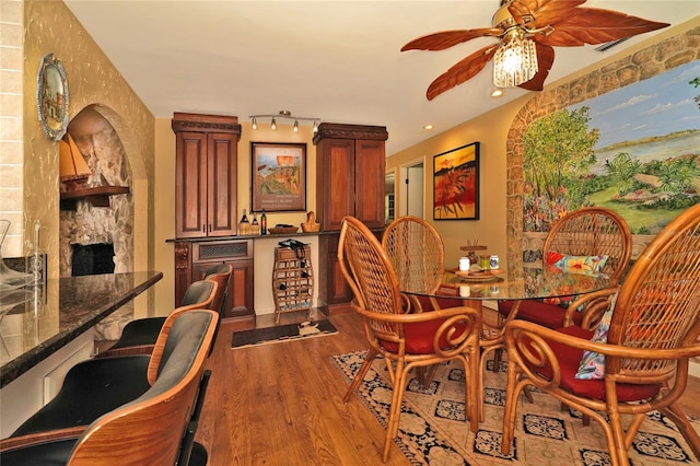 dining space featuring hardwood / wood-style flooring, ceiling fan, and a fireplace