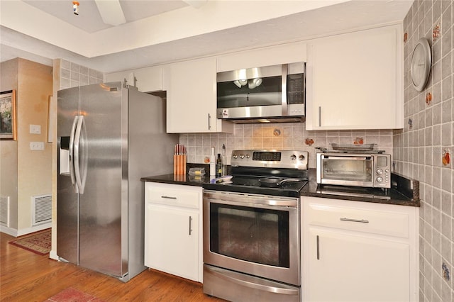 kitchen featuring stainless steel appliances, white cabinetry, and backsplash