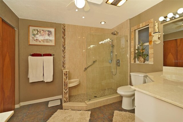 bathroom featuring tile patterned floors, vanity, toilet, and a tile shower