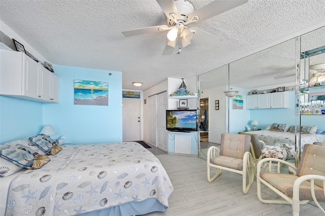 bedroom featuring ceiling fan, a textured ceiling, a closet, and light wood-type flooring