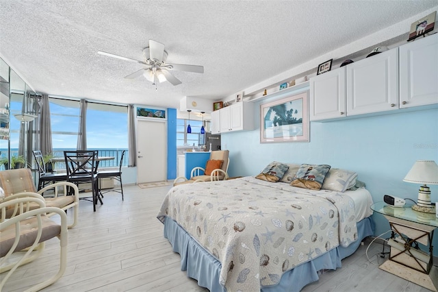 bedroom with ceiling fan, stainless steel refrigerator with ice dispenser, a textured ceiling, and light hardwood / wood-style floors