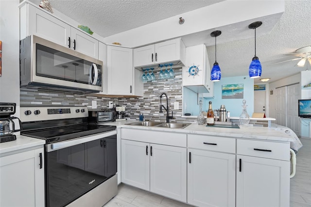 kitchen featuring white cabinetry, stainless steel appliances, decorative backsplash, decorative light fixtures, and sink