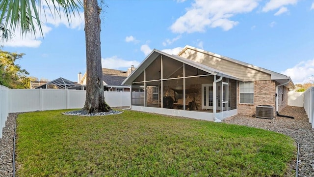 rear view of house featuring a sunroom and a lawn