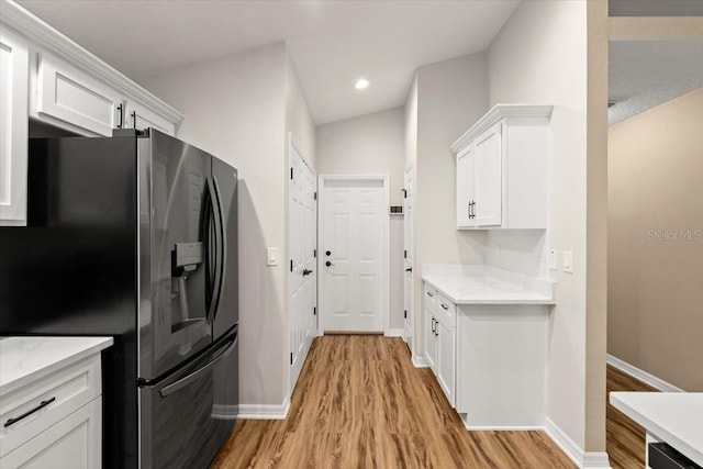 kitchen featuring white cabinets, stainless steel fridge with ice dispenser, lofted ceiling, and light hardwood / wood-style flooring