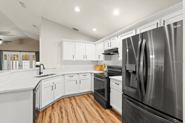 kitchen with kitchen peninsula, vaulted ceiling, appliances with stainless steel finishes, sink, and white cabinetry