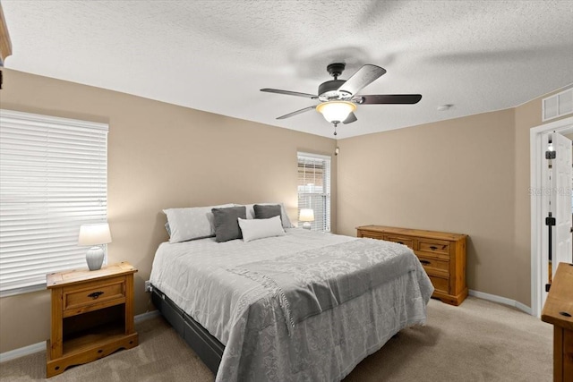 bedroom featuring ceiling fan, light colored carpet, and a textured ceiling