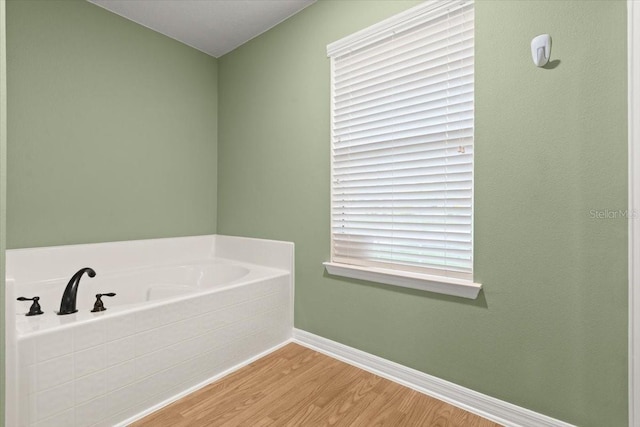 bathroom with a washtub and hardwood / wood-style floors