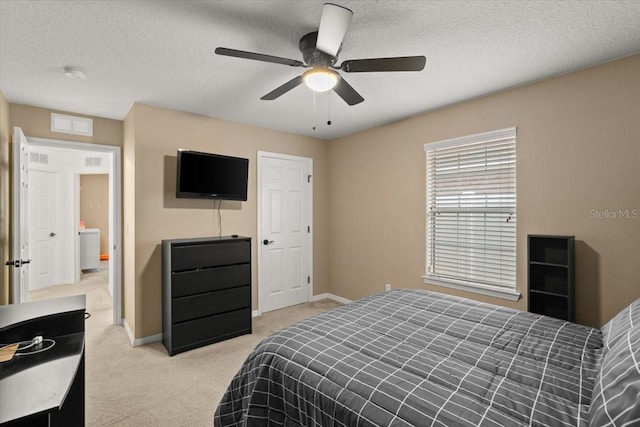 bedroom with ceiling fan, light colored carpet, and a textured ceiling