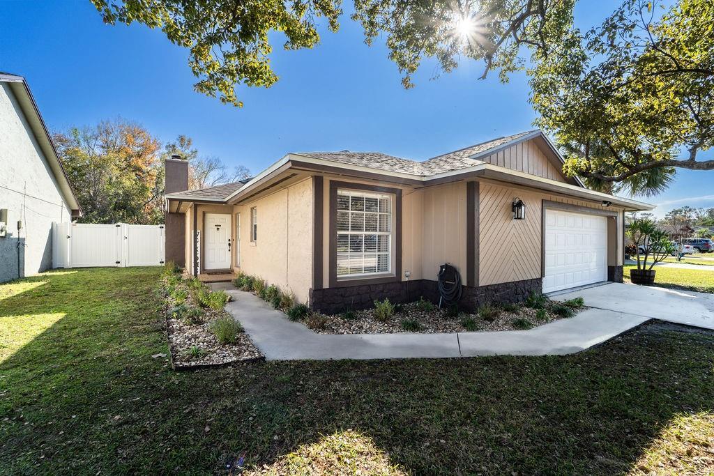 1413 La Paloma Cir, Winter Springs, FL 32708 - view of side of home with a gate, a chimney, an attached garage, and a lawn